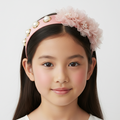 Young girl wearing a decorative headband with flowers and pearls on a white background