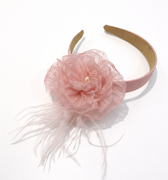 Pink headband with a flower and feathers on a white background