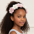 Young girl wearing a floral headband with pink and white flowers on a light background