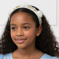 Young girl wearing a decorative headband against a white background