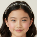Young girl wearing a decorative headband with a plain background