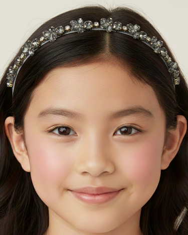 Young girl wearing a decorative headband with a plain background