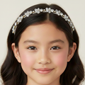 Young girl wearing a decorative headband with a plain background