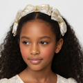 Young girl wearing a decorative headband with a bow on a plain background