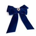 Blue velvet bow with a decorative center on a white background