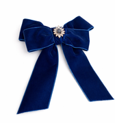 Blue velvet bow with a decorative center on a white background