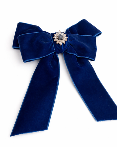 Blue velvet bow with a decorative center on a white background