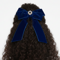 Blue velvet hair bow on curly hair against a white background