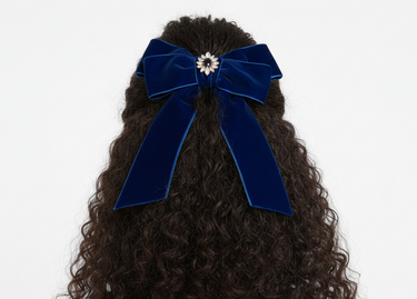 Blue velvet hair bow on curly hair against a white background