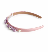 Pink headband with purple bow and pearls on a white background