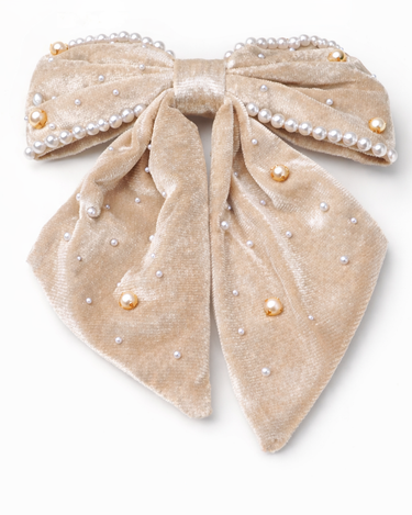 Beige velvet bow with pearl embellishments on a white background