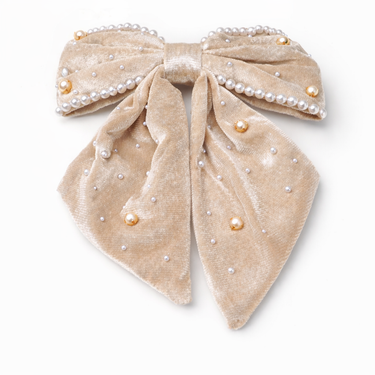 Beige velvet bow with pearl embellishments on a white background