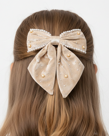 Beige bow hair clip with pearls on a person's head against a white background