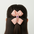 Pink hair bow with a decorative center on a mannequin head against a white background