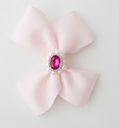 Pink bow with a central gemstone on a light gray background
