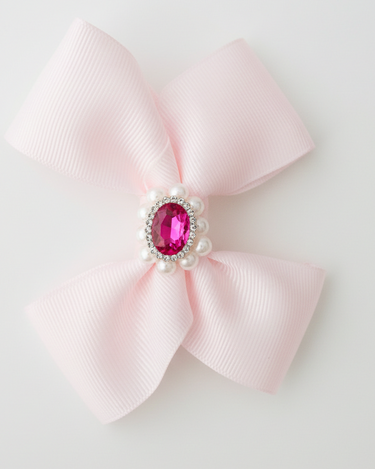 Pink bow with a central gemstone on a light gray background