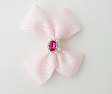 Pink bow with a central gemstone on a light gray background