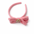 Pink velvet bow headband with a decorative center on a white background