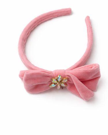 Pink velvet bow headband with a decorative center on a white background