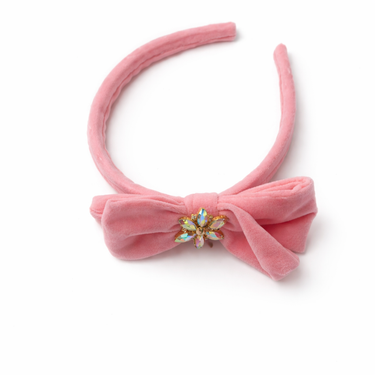 Pink velvet bow headband with a decorative center on a white background