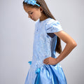 Girl in royal blue taffeta dress with sequin lace front and velvet bow accents.