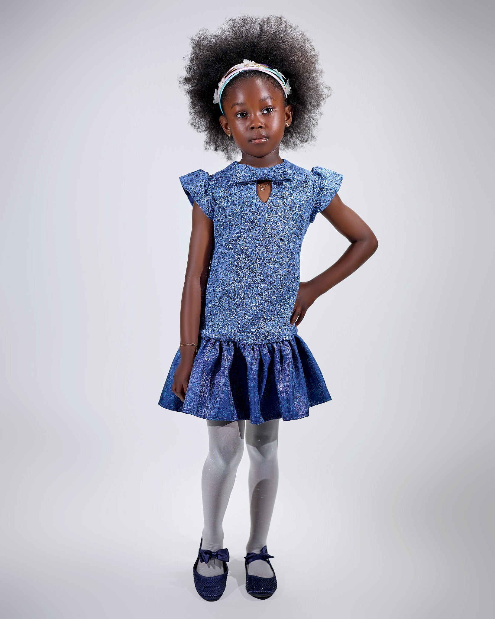 Girl in sequined lace and denim-look taffeta dress with flutter sleeves.