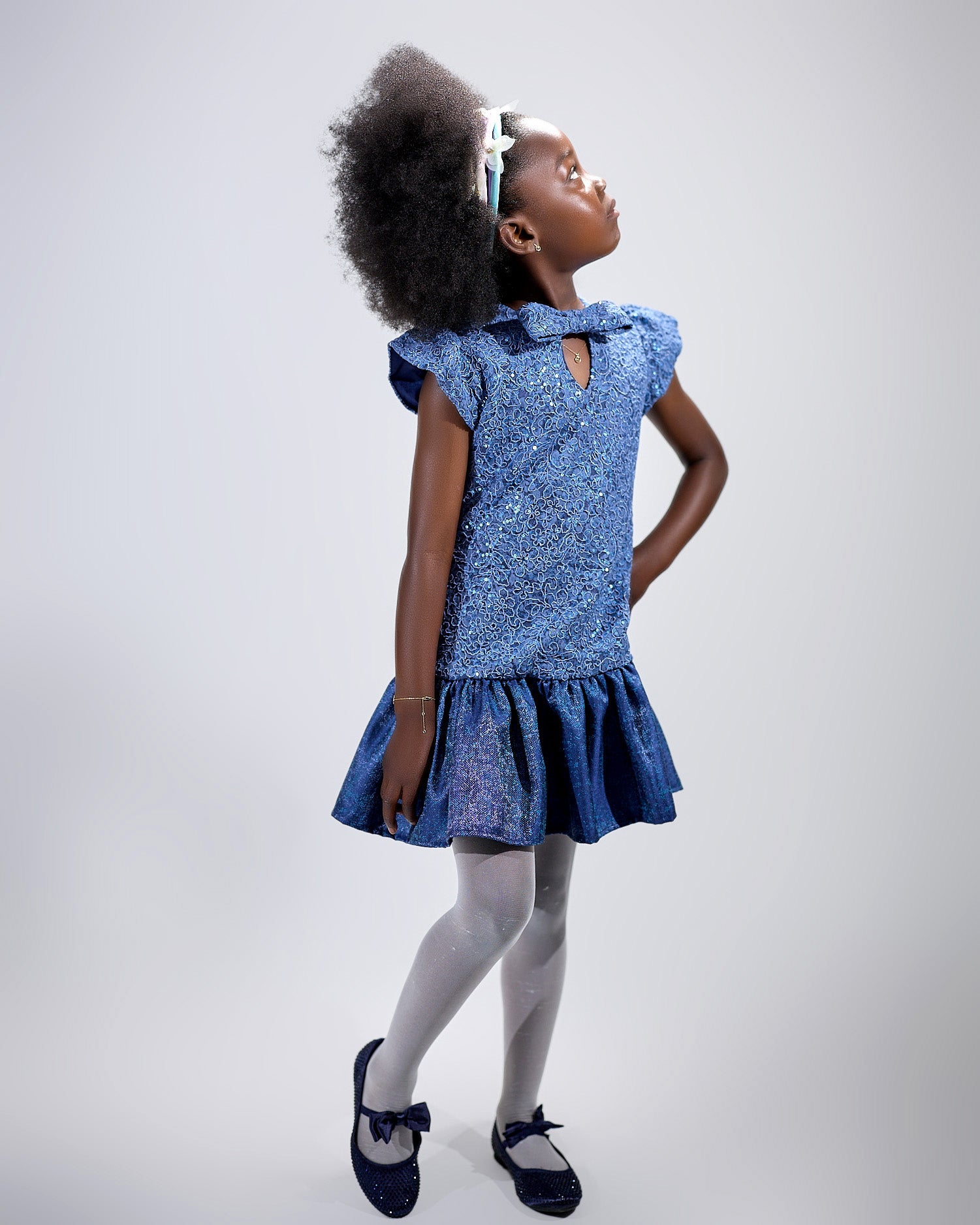 Girl in sequined lace and denim-look taffeta dress with flutter sleeves.