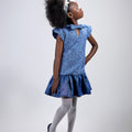 Girl in sequined lace and denim-look taffeta dress with flutter sleeves.