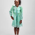 Girl in mint glitter jersey dress with silk organza overshirt and feather trim.