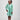 Girl in mint glitter jersey dress with silk organza overshirt and feather trim.