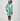 Girl in mint glitter jersey dress with silk organza overshirt and feather trim.