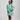 Girl in mint glitter jersey dress with silk organza overshirt and feather trim.