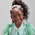 Girl in mint glitter jersey dress with silk organza overshirt and feather trim.