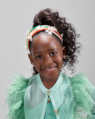 Girl in mint glitter jersey dress with silk organza overshirt and feather trim.
