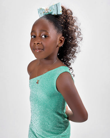 Girl in mint glitter jersey dress with silk organza overshirt and feather trim.
