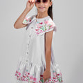 Girl in floral and flamingo print dress with scalloped cape and gathered skirt.