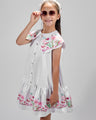 Girl in floral and flamingo print dress with scalloped cape and gathered skirt.