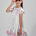Girl in floral and flamingo print dress with scalloped cape and gathered skirt.