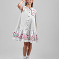 Girl in floral and flamingo print dress with scalloped cape and gathered skirt.