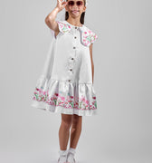 Girl in floral and flamingo print dress with scalloped cape and gathered skirt.
