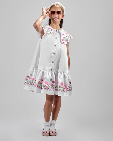 Girl in floral and flamingo print dress with scalloped cape and gathered skirt.