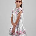 Girl in floral and flamingo print dress with scalloped cape and gathered skirt.