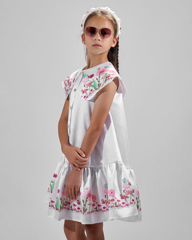 Girl in floral and flamingo print dress with scalloped cape and gathered skirt.