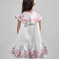 Girl in floral and flamingo print dress with scalloped cape and gathered skirt.