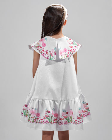 Girl in floral and flamingo print dress with scalloped cape and gathered skirt.