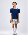 Girl in navy velvet and floral brocade dress with puff sleeves and scalloped detail.