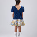 Girl in navy velvet and floral brocade dress with puff sleeves and scalloped detail.