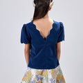 Girl in navy velvet and floral brocade dress with puff sleeves and scalloped detail.