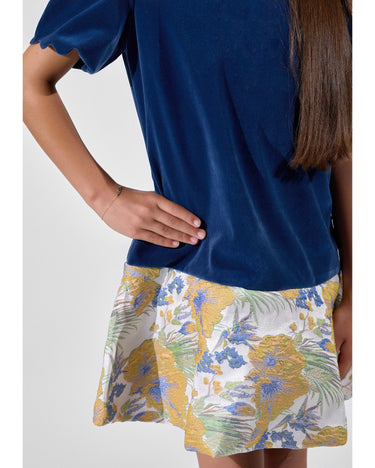 Girl in navy velvet and floral brocade dress with puff sleeves and scalloped detail.