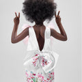 Girl in taffeta A-line dress with flamingo print, tulle sleeves, and back bow.
